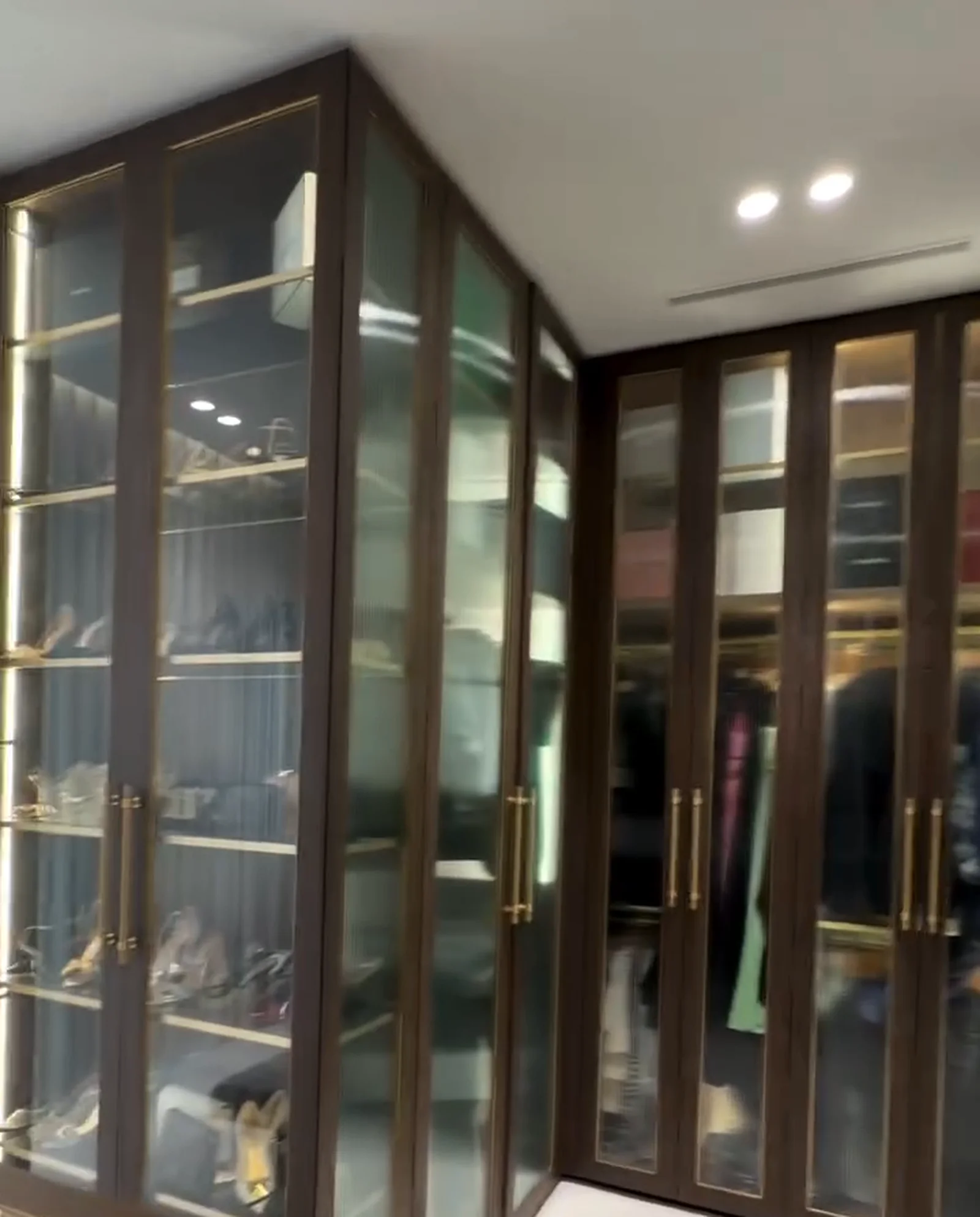 Dressing room with glass-fronted timber cabinetry and brass handles