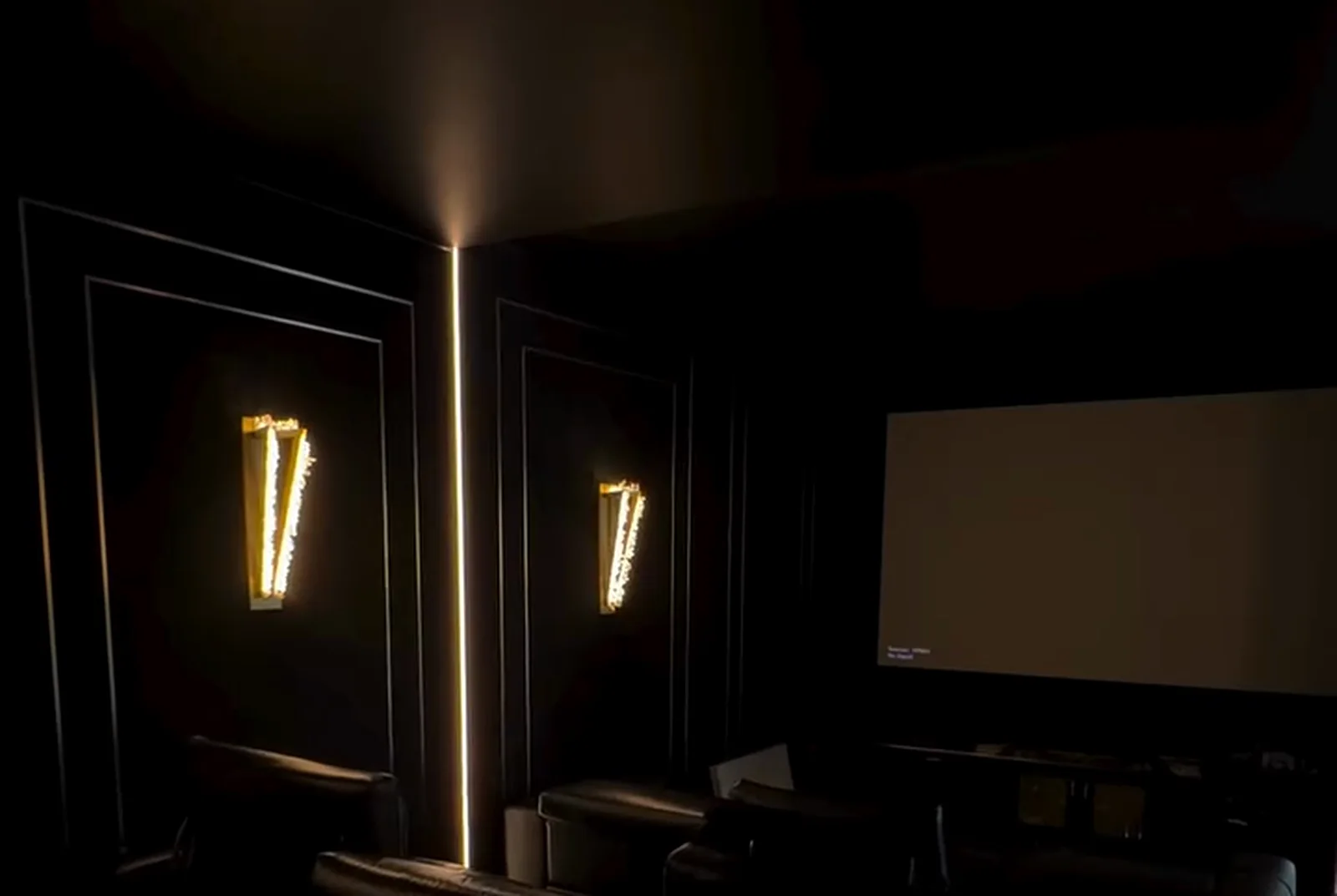 Home theatre with panelled acoustic walls and wall sconces